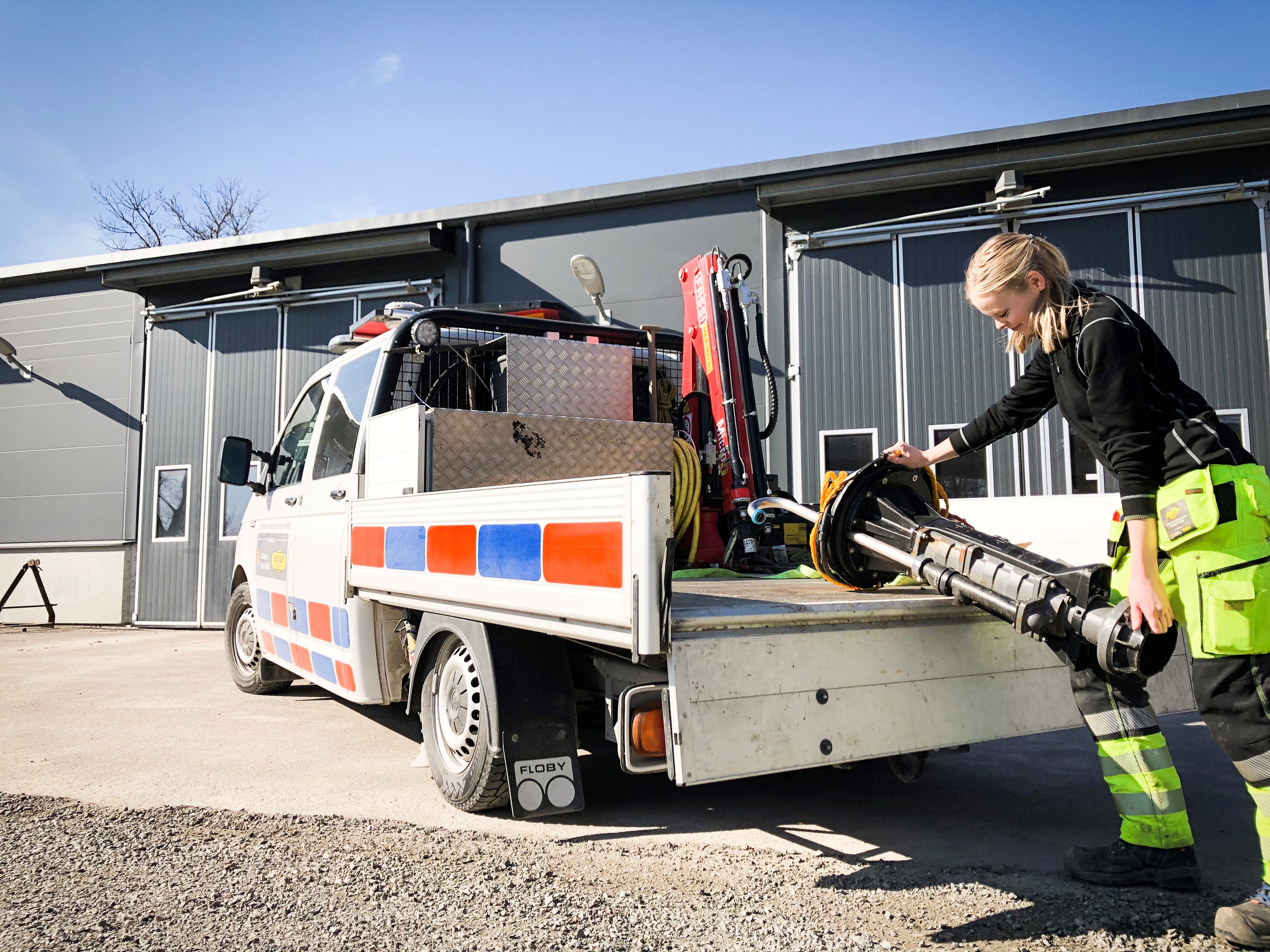 Bild på Maria Styrlander som lastar upp utrustning på sin arbetsbil